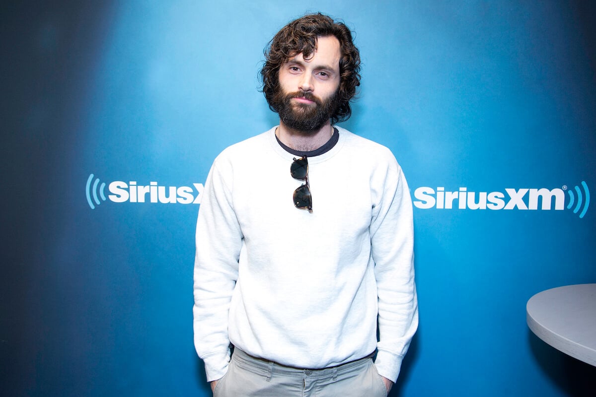 Penn Badgley standing with his hands in his pockets