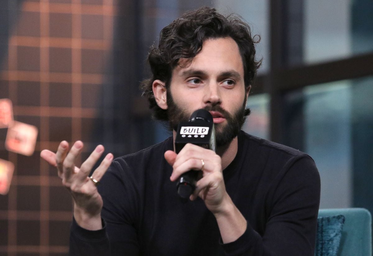 Penn Badgley speaks into a microphone.