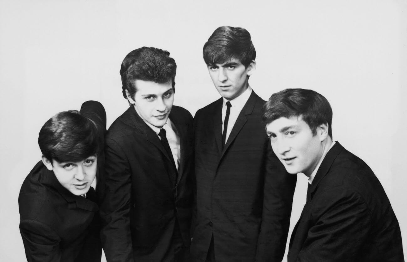 A black and white picture of Paul McCartney, Pete Best, George Harrison, and John Lennon wearing suits.