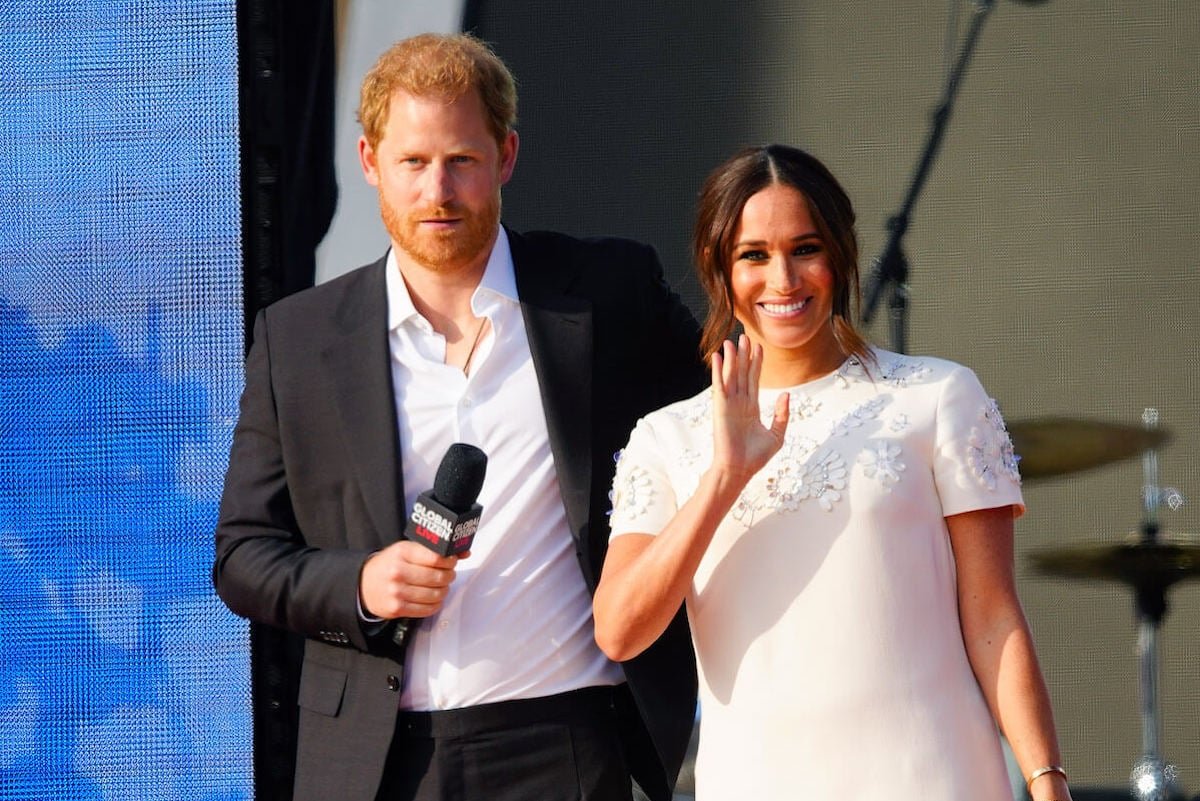 Prince Harry and Meghan Markle, whose children are Prince Archie and Princess Lilibet following a title announcement, stand onstage and look on