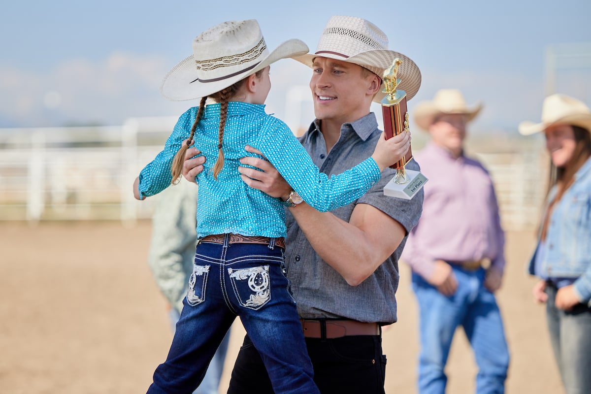 Tyler Jacob Moore, wearing a cowboy had and holding a little girl, in Hallmark Channel's 'Ride'