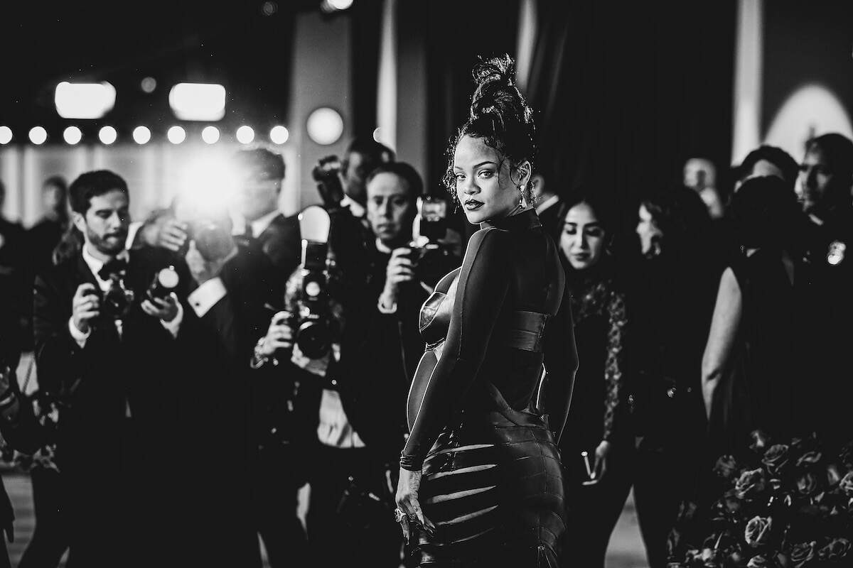 Pop star Rihanna poses for photos in a black full-body dress at the 2023 Oscars