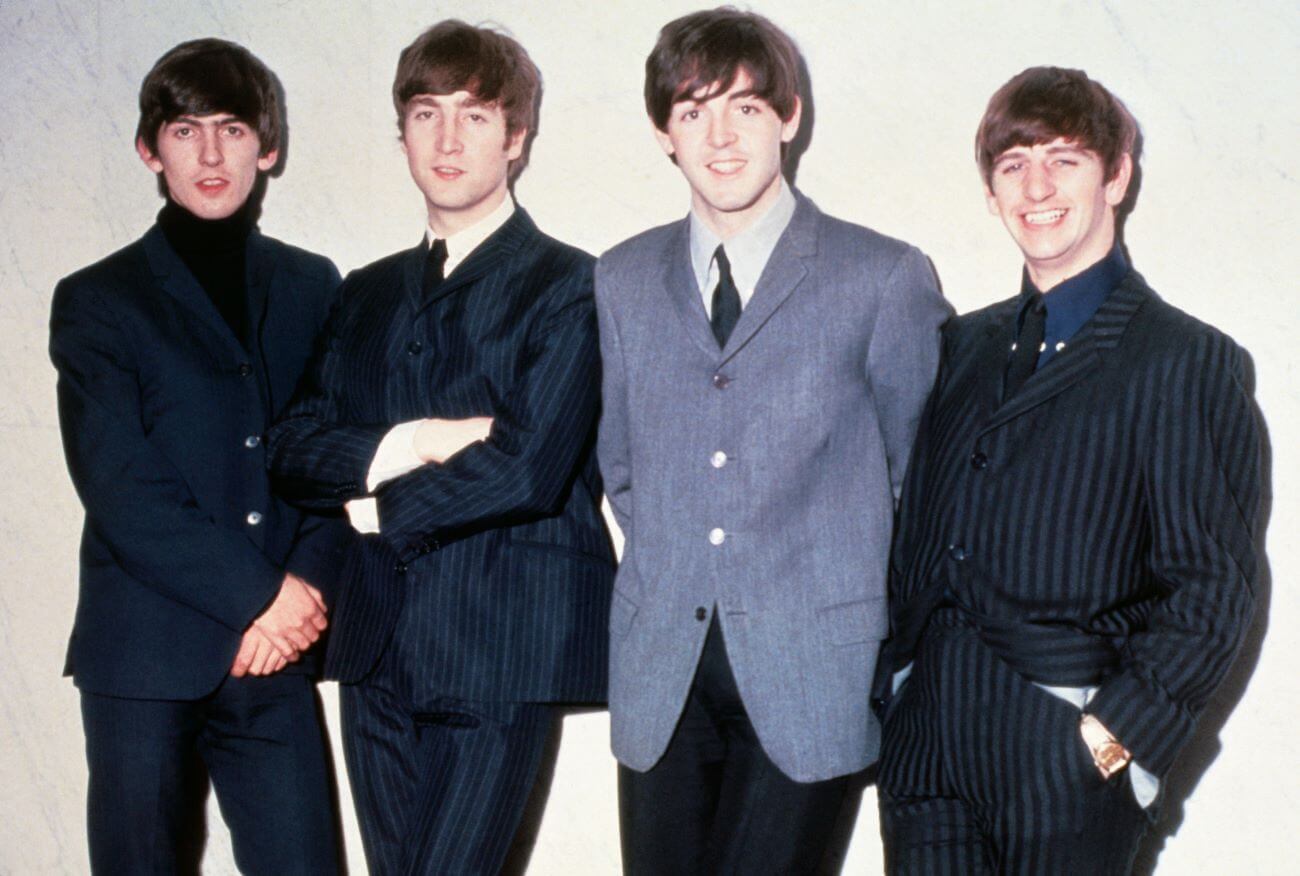 George Harrison, John Lennon, Paul McCartney, and Ringo Starr of The Beatles lean against a white wall.