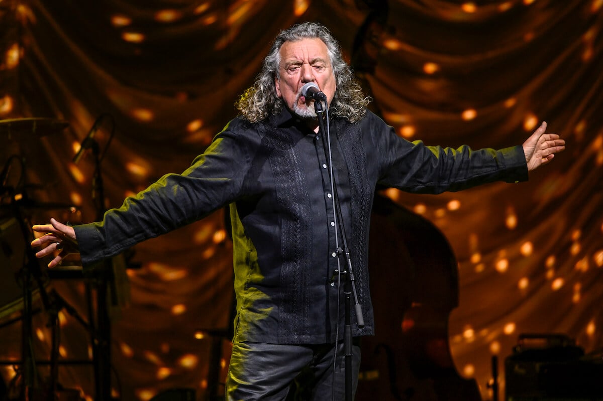 Robert Plant singing into a microphone with his arms outstretched