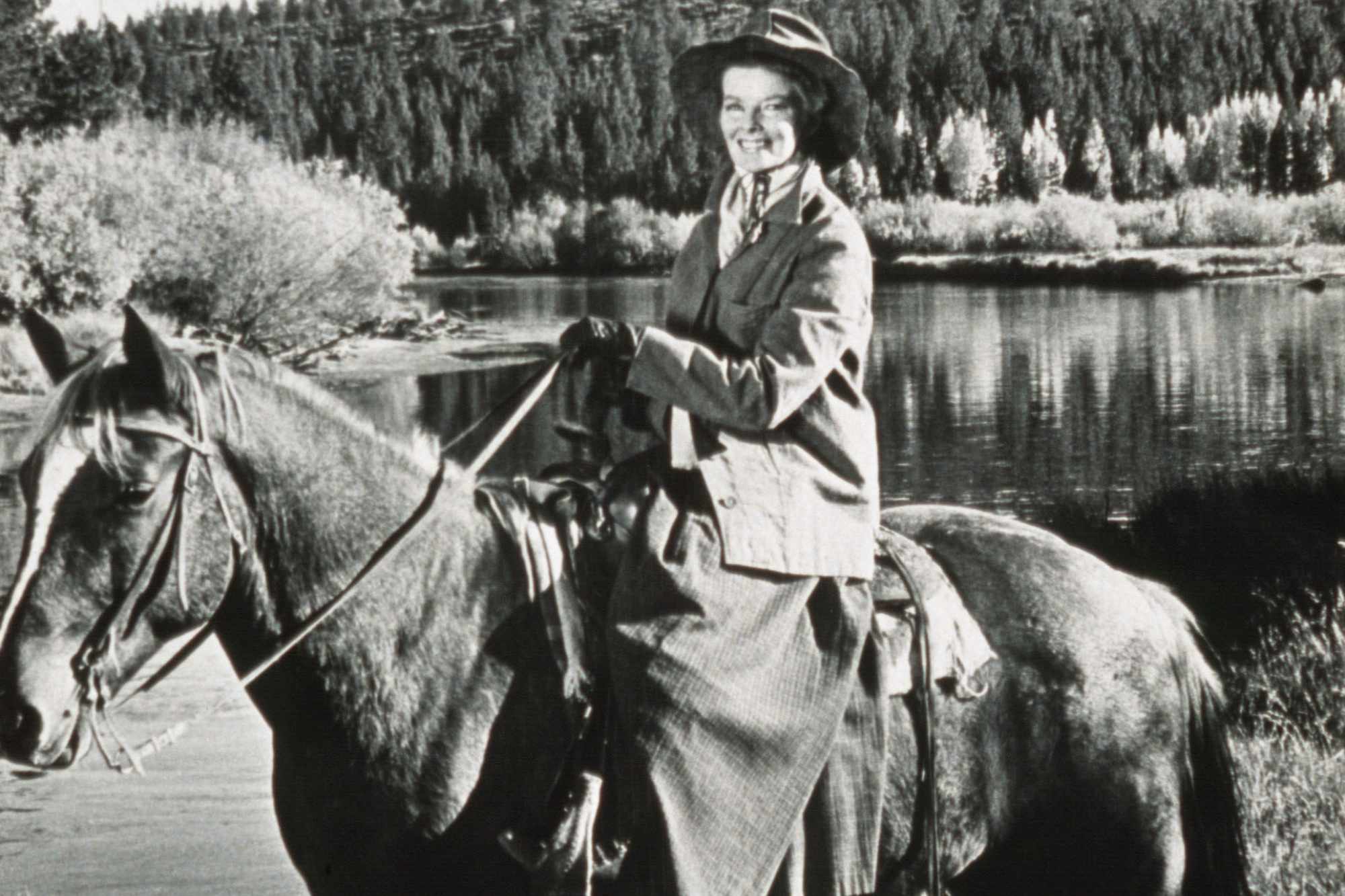 'Rooster Cogburn' Katharine Hepburn smiling on the back of the horse in a black-and-white picture.