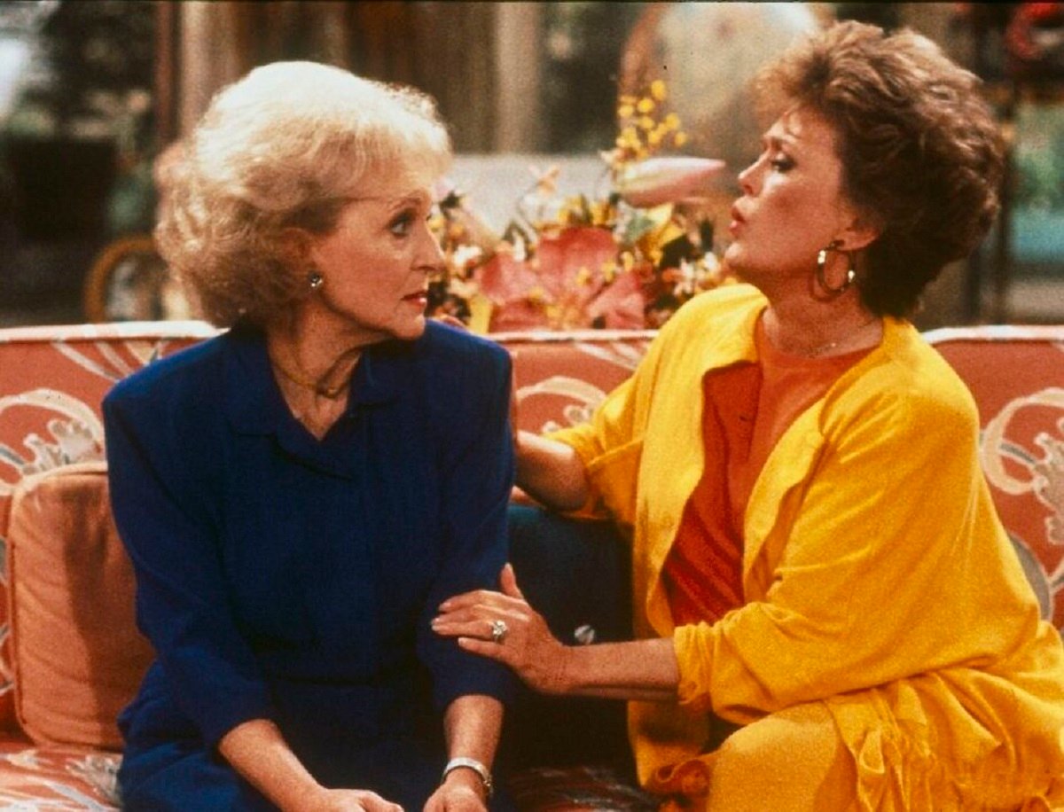 Rose Nylund and Blanche Devereaux sit together in their living room on 'The Golden Girls'. Rose moved in with Blanche after she moved to Miami from St. Olaf, Minnesota