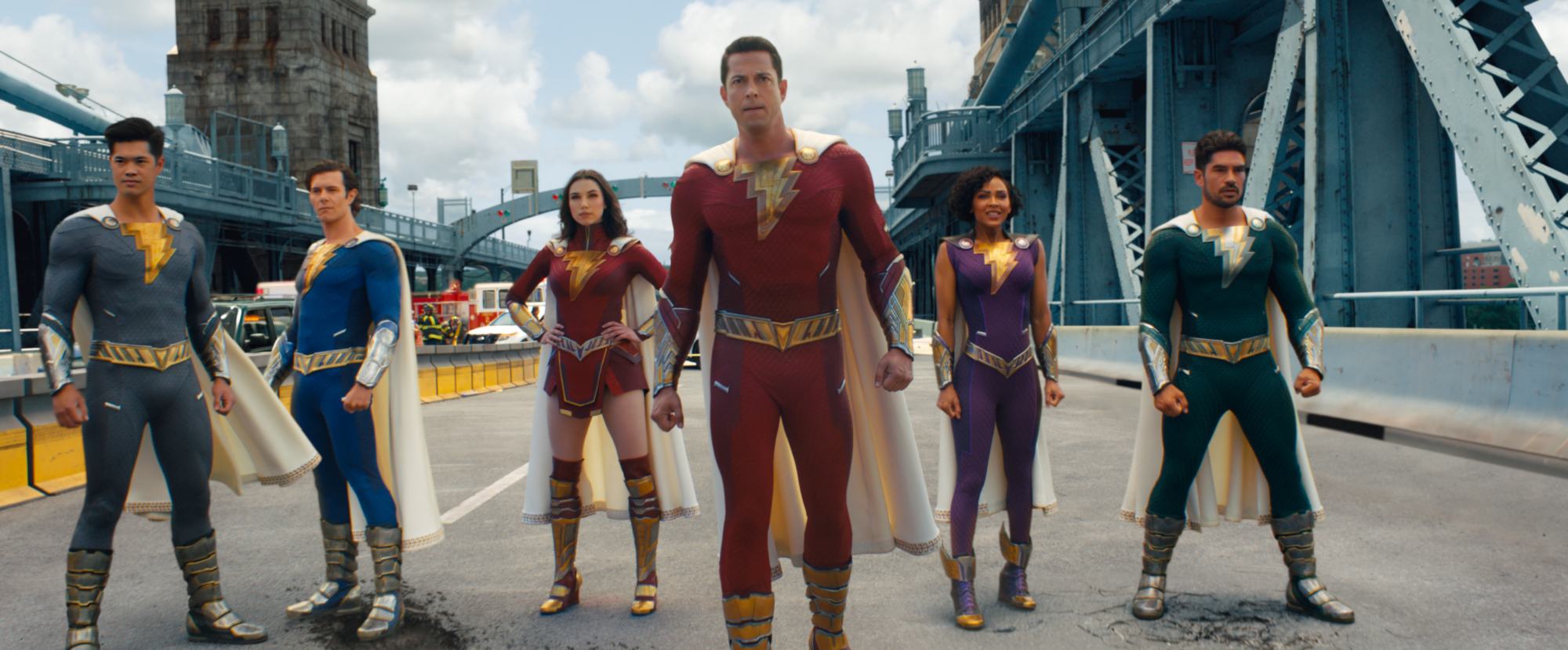 'Shazam! Fury of the Gods' Ross Butler as Super Hero Eugene, Adam Brody as Super Hero Freddy, Grace Caroline Currey as Super Hero Mary, Zachary Levi as Shazam, Meagan Good as Super Hero Darla, and D.J. Cotrona as Super Hero Pedro standing side-to-side on a bridge.