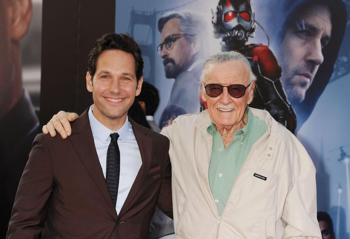 Stan Lee standing next to Paul Rudd with his arm around him