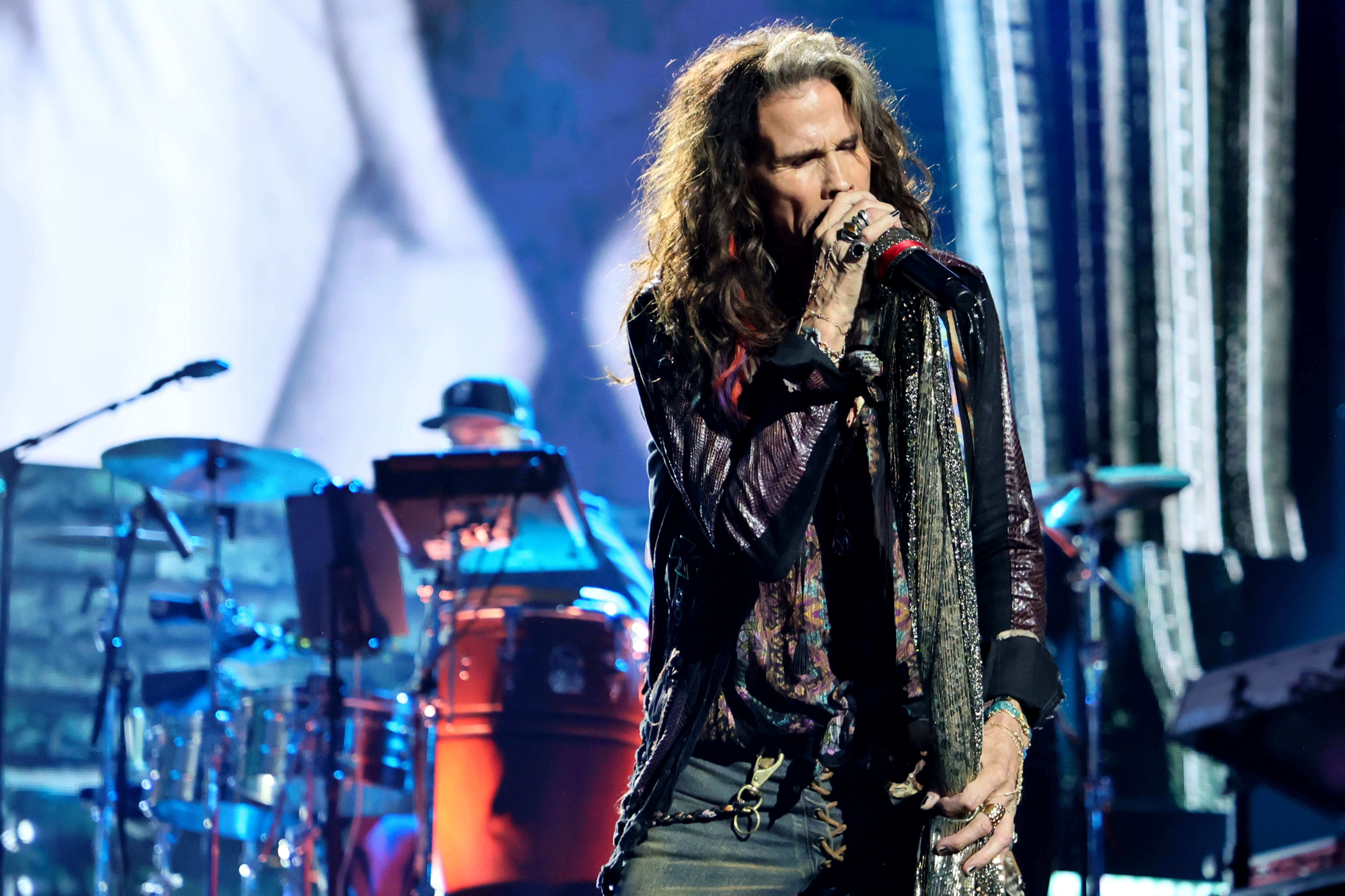 Steven Tyler of Aerosmith singing into a microphone on stage