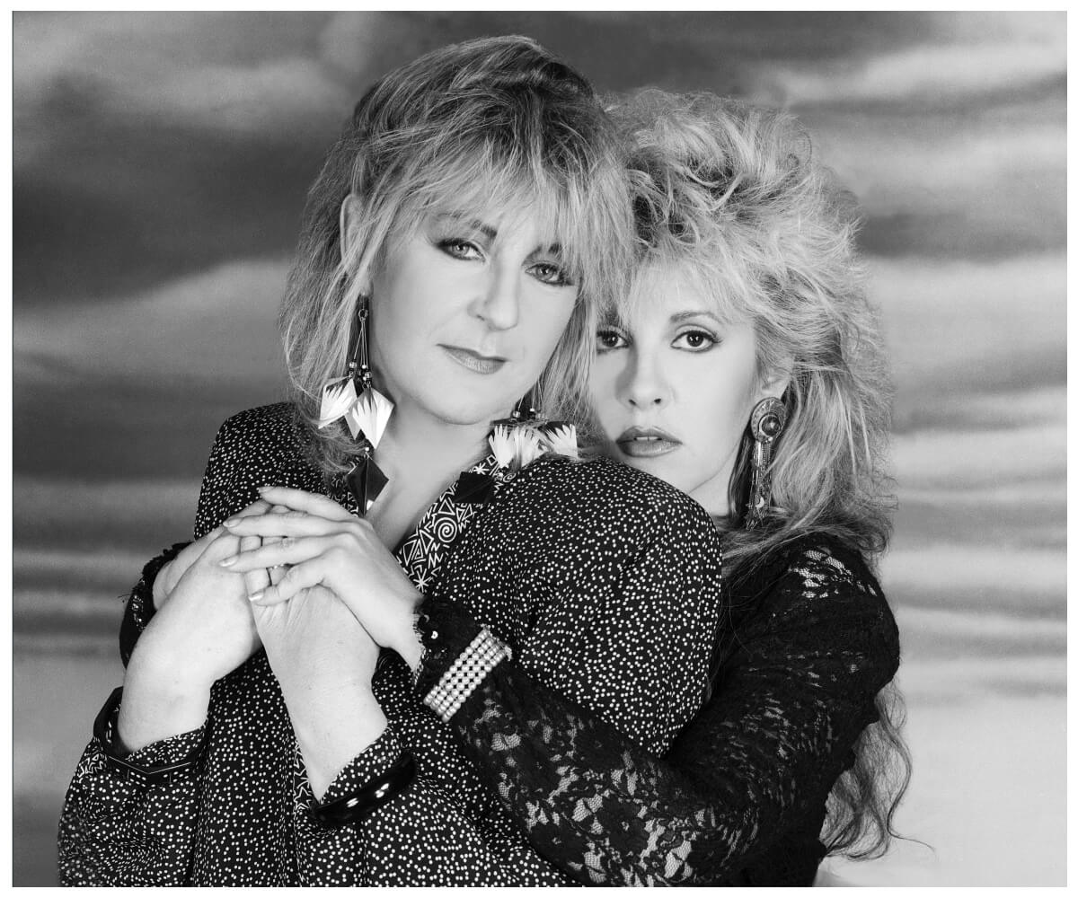 Black and white portrait of Fleetwood Mac stars Christine McVie and Stevie Nicks embracing.