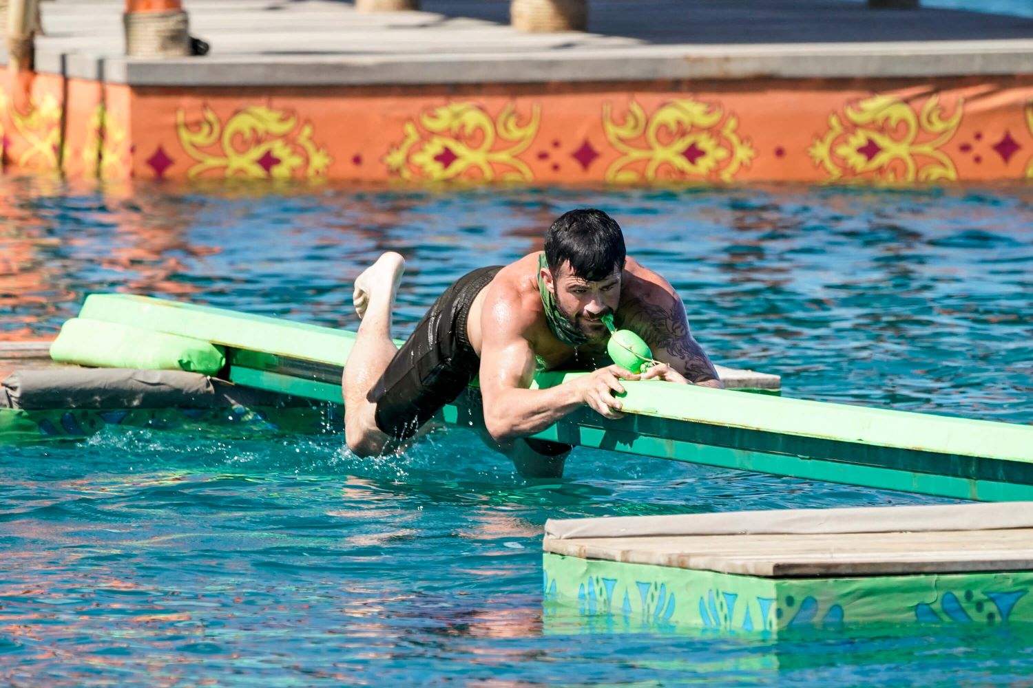 Danny Massa, one of the 'Survivor 44' castaways, competes in an Immunity Challenge in episode 4 by crawling on a thin beam suspended above the water wearing black shorts.