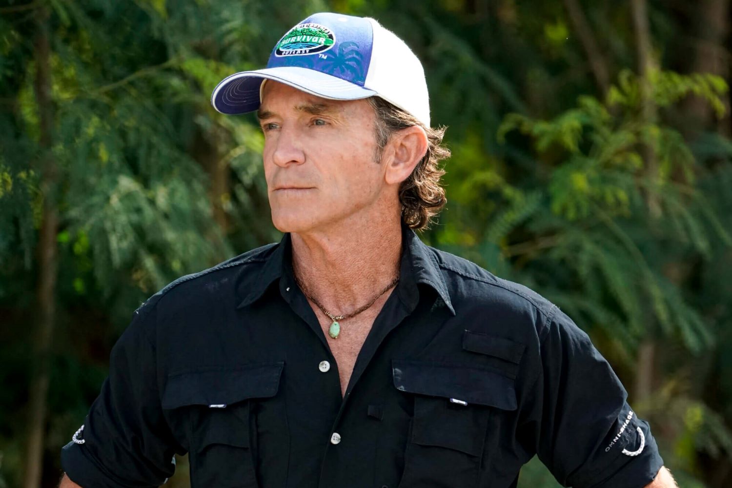 Jeff Probst, the host and executive producer of 'Survivor' who helps come up with the show's rules, wears a black safari shirt and white and blue 'Survivor' baseball cap.