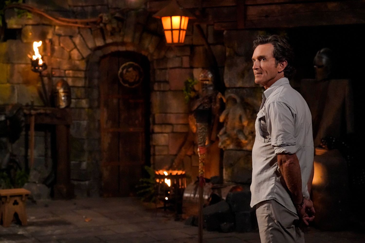Jeff Probst, who has hosted all 44 seasons of 'Survivor' on CBS, appears at Tribal Council wearing a light gray button-up shirt and tan pants.