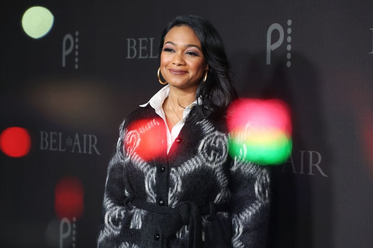 Tatyana Ali poses for pictures inb front of a backdrop with the Peacock logo.
