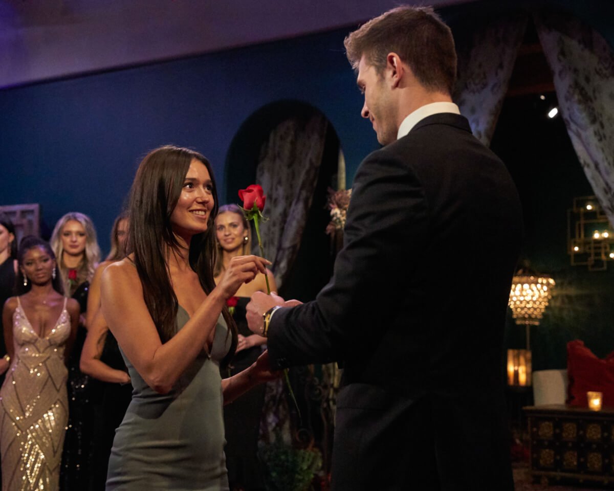 During 'The Bachelor' Season 27, Zach gives Greer a rose. She wears a olive green, low-cut dress.