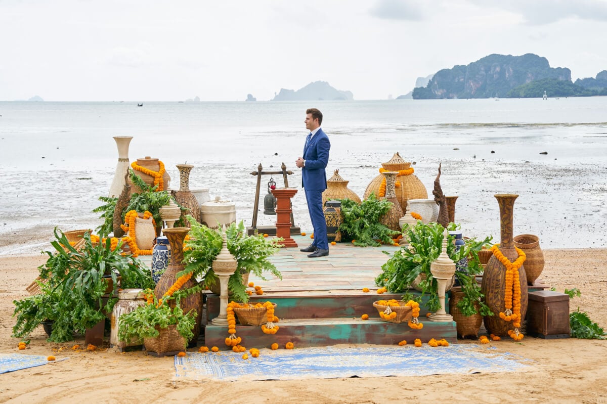 During The Bachelor Season 27 finale, Zach Shallcross stands on the beach in Krabi wearing a blue suit.