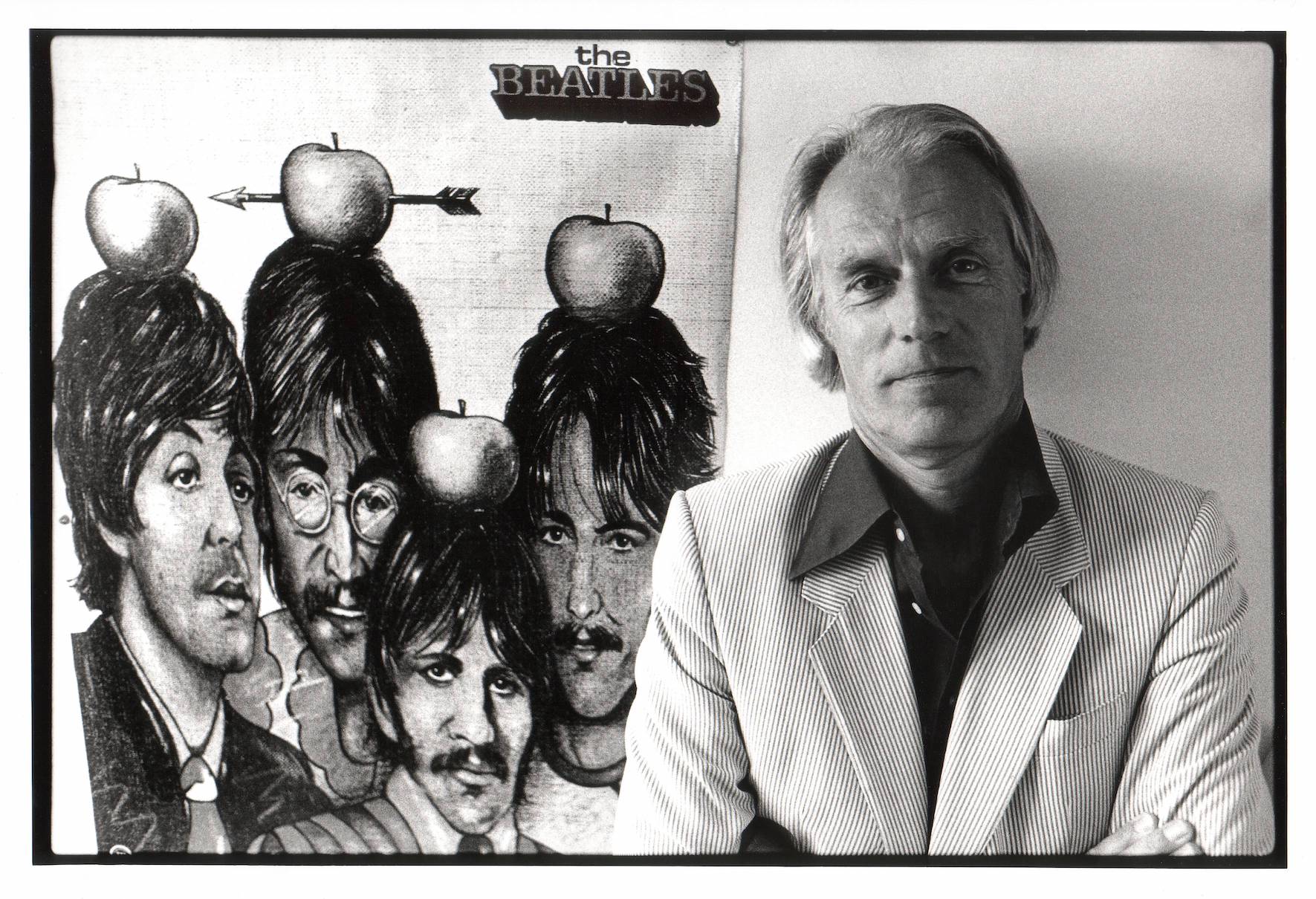 Producer George Martin in front of a poster of The Beatles