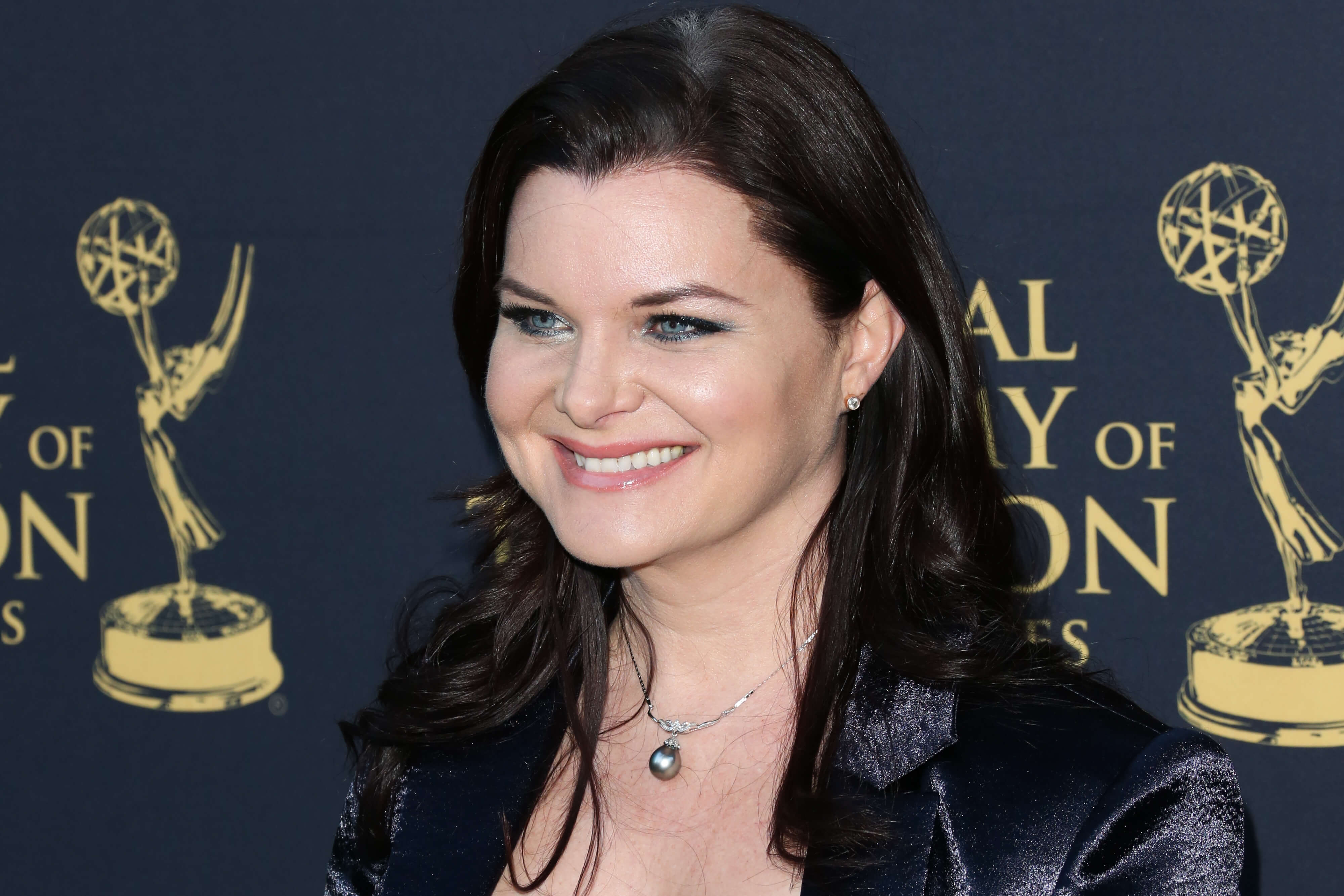 'The Bold and the Beautiful' star Heather Tom dressed in a black pantsuit; smiling for a red carpet photo.