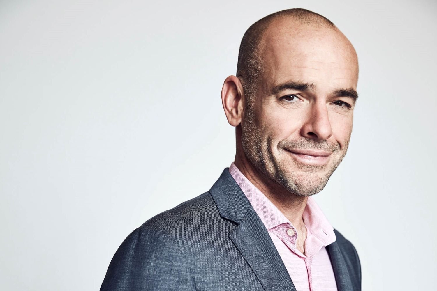 Paul Blackthorne, who guest stars in 'The Company You Keep' Season 1 Episode 5, wears a dark gray suit over a light pink button-up shirt.