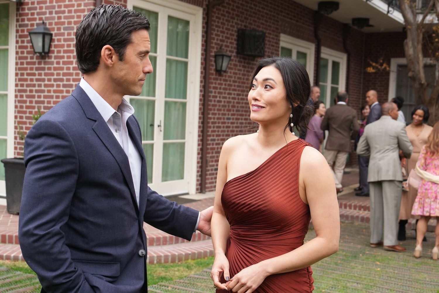 Milo Ventimiglia as Charlie and Catherine Haena Kim as Emma in 'The Company You Keep' Episode 4, which doesn't air tonight, March 12. Charlie wear a dark blue suit. Emma wears a dark red one-shoulder dress.