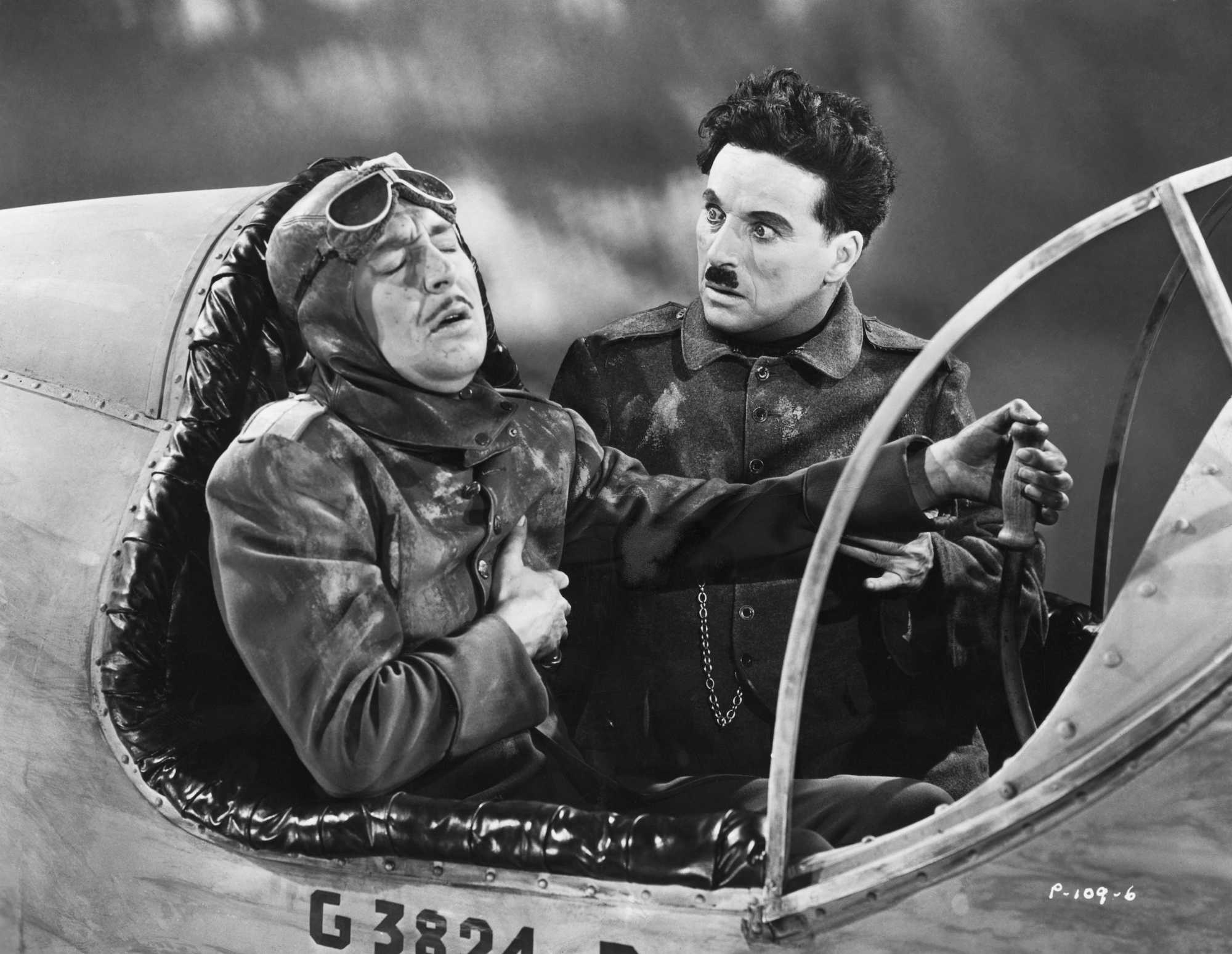 'The Great Dictator' Charlie Chaplin as Hynkel - Dictator of Tomania. He's looking at an unknown actor in a jet cockpit, clutching onto his chest.