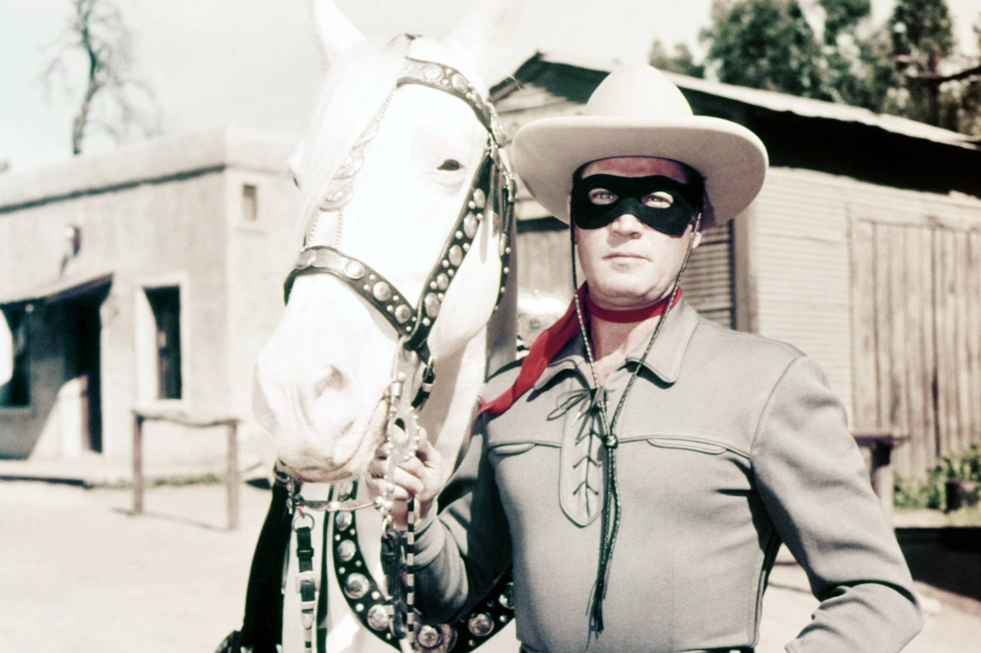 'The Lone Ranger' Clayton Moore as the Lone Ranger. He's wearing his Western costume and mask, while standing next to a white horse.