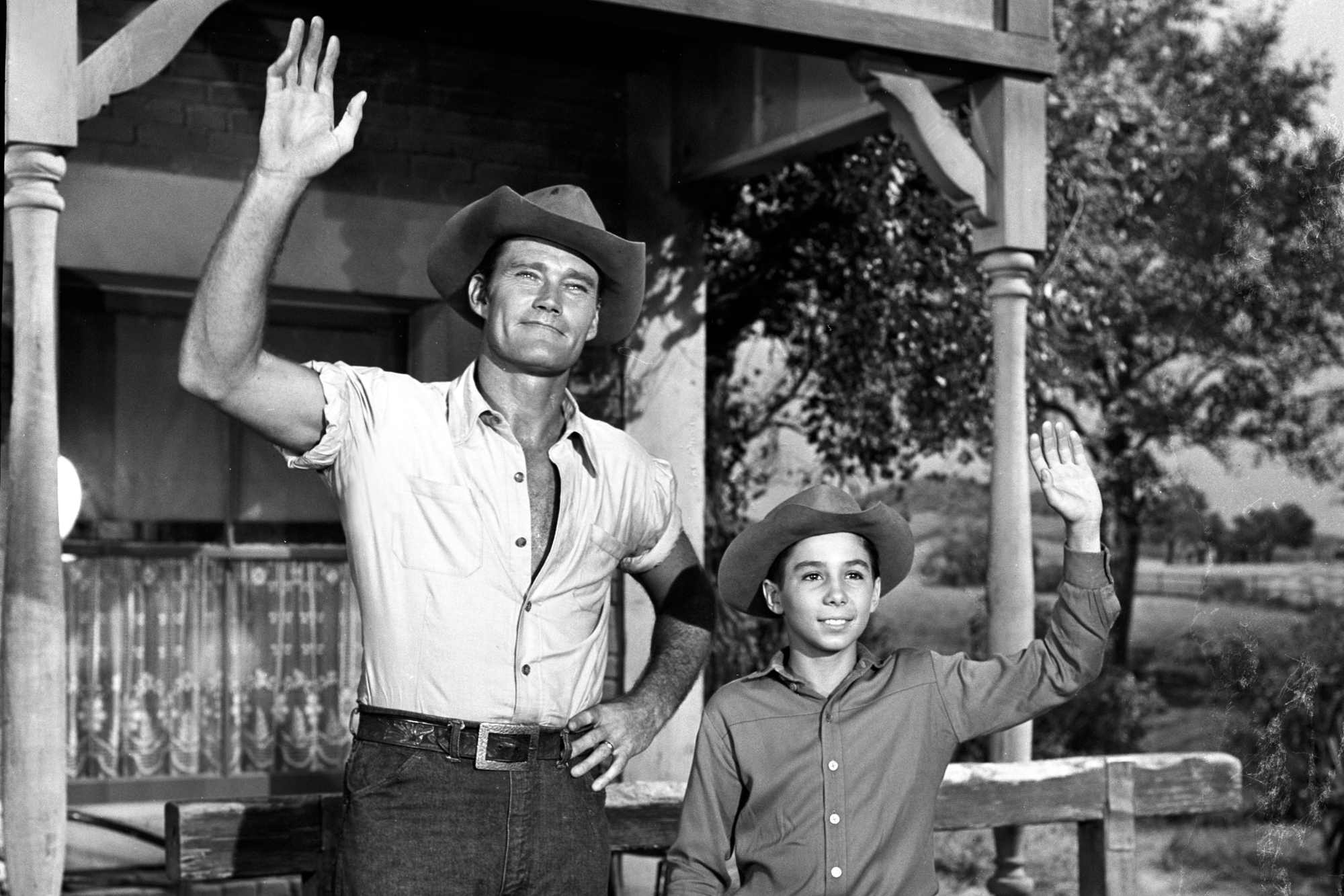 'The Rifleman' Chuck Connors as Lucas and Johnny Crawford as Mark McCain waving in front of a house.