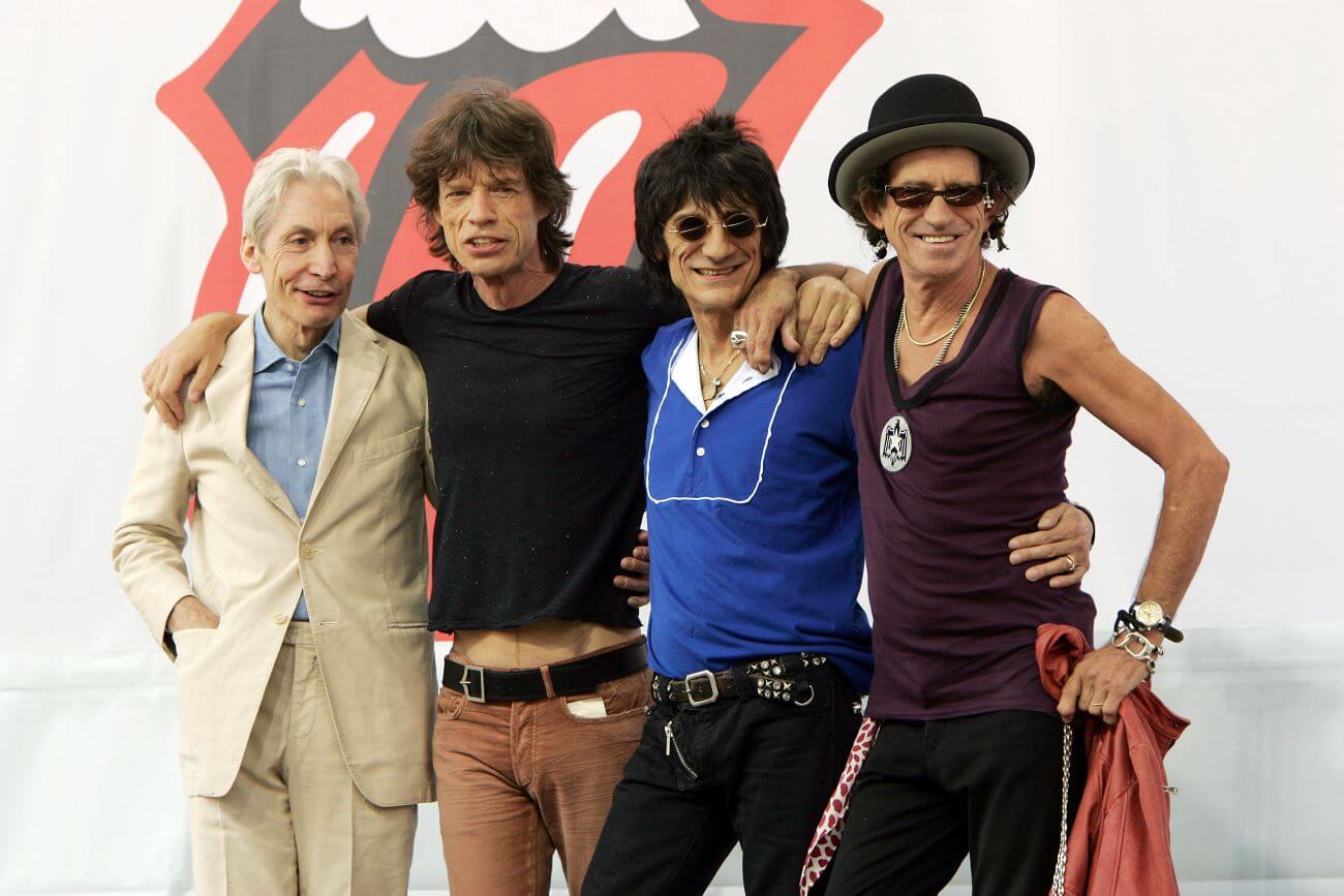 Charlie Watts, Mick Jagger, Ronnie Woods, and Keith Richards pose together in front of the Rolling Stones mouth.