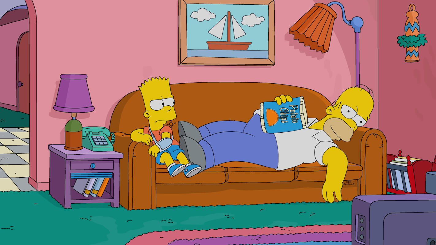 'The Simpsons': Bart sits and Homer lies down on the couch.