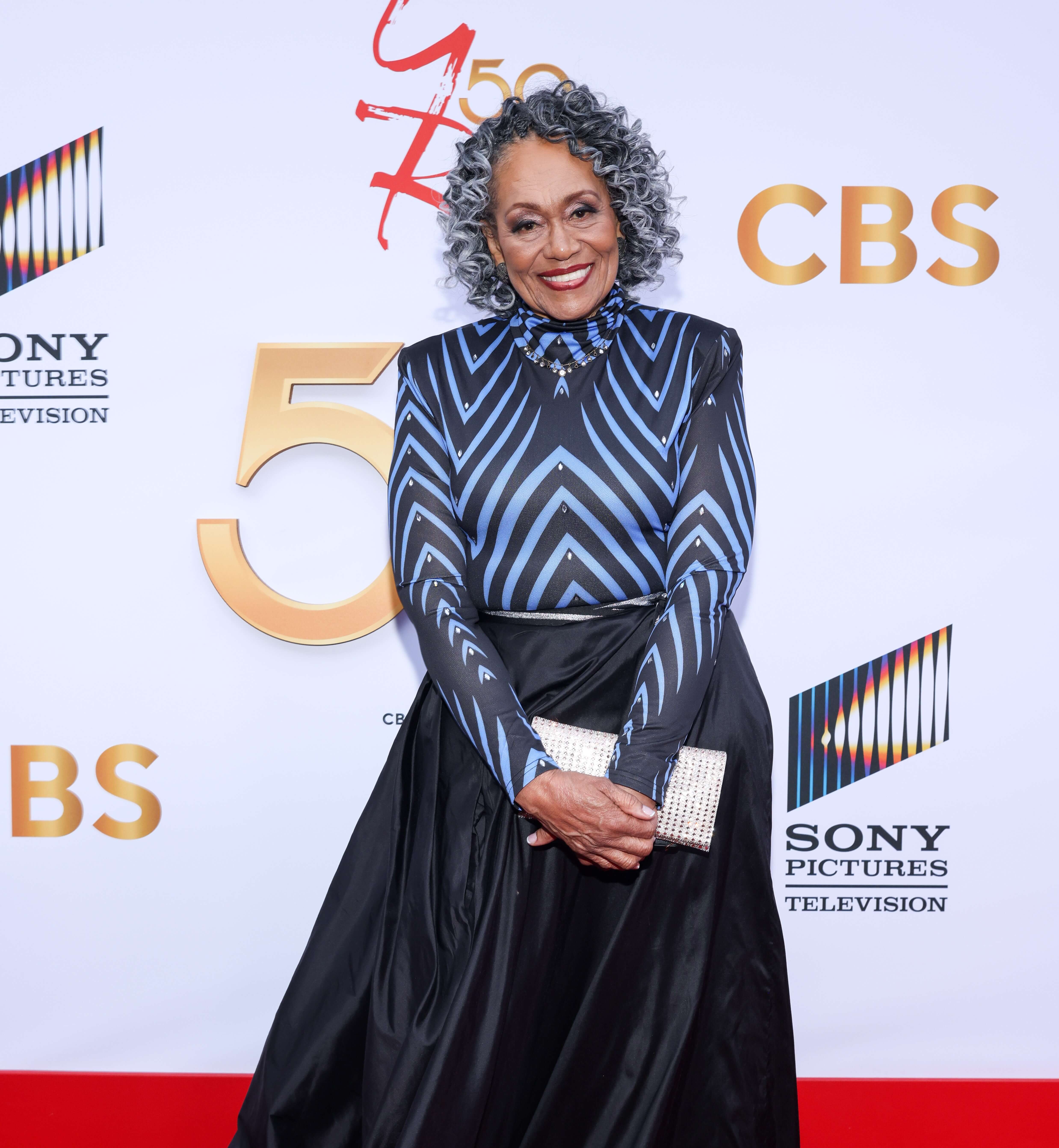 'The Young and the Restless' star Veronica Redd in a black dress; poses on the red carpet of the show's 50th anniversary celebration.