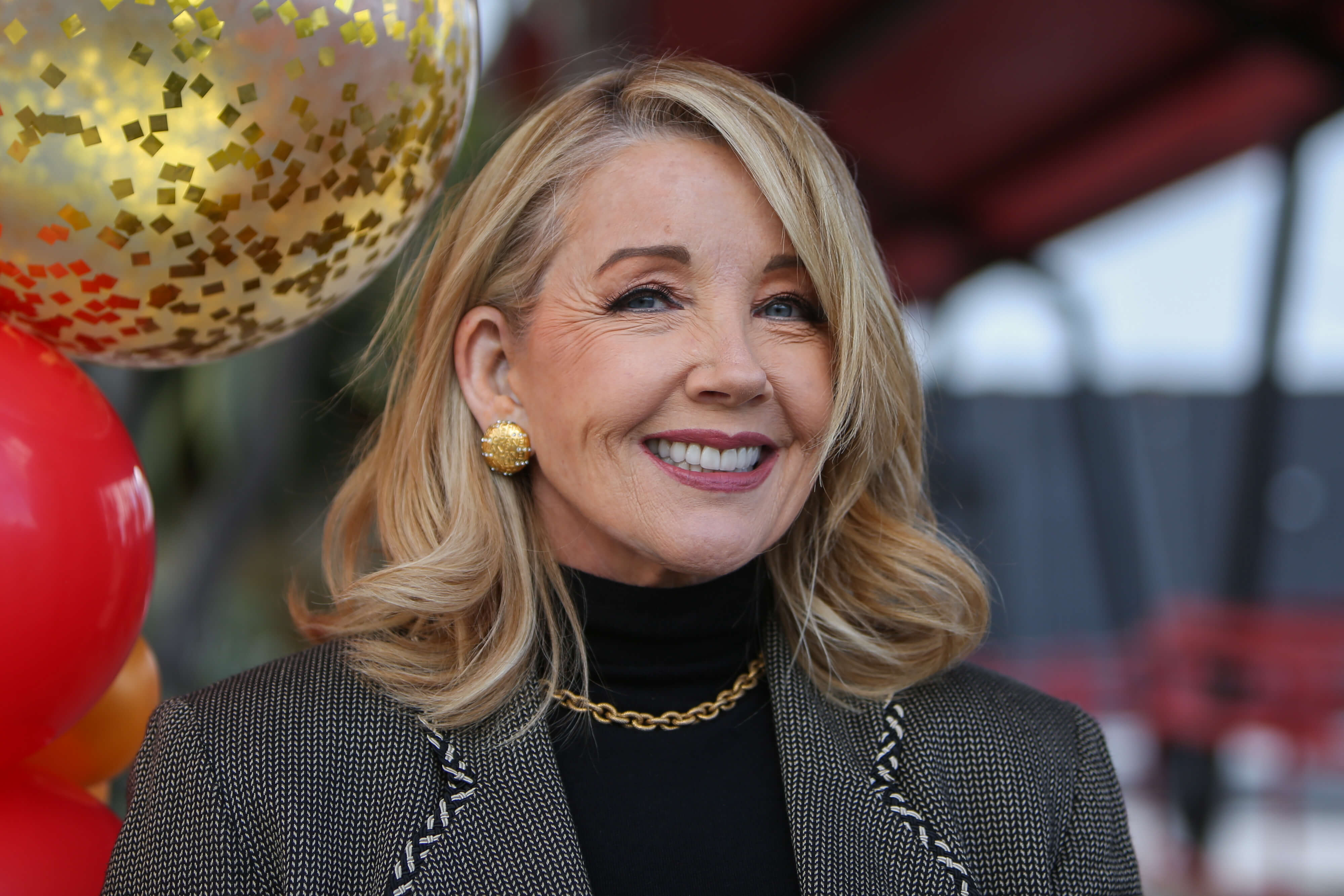 'The Young and the Restless' star Melody Thomas Scott dressed in a black shirt and grey blazer; smiles during a time capsule opening for the soap opera.