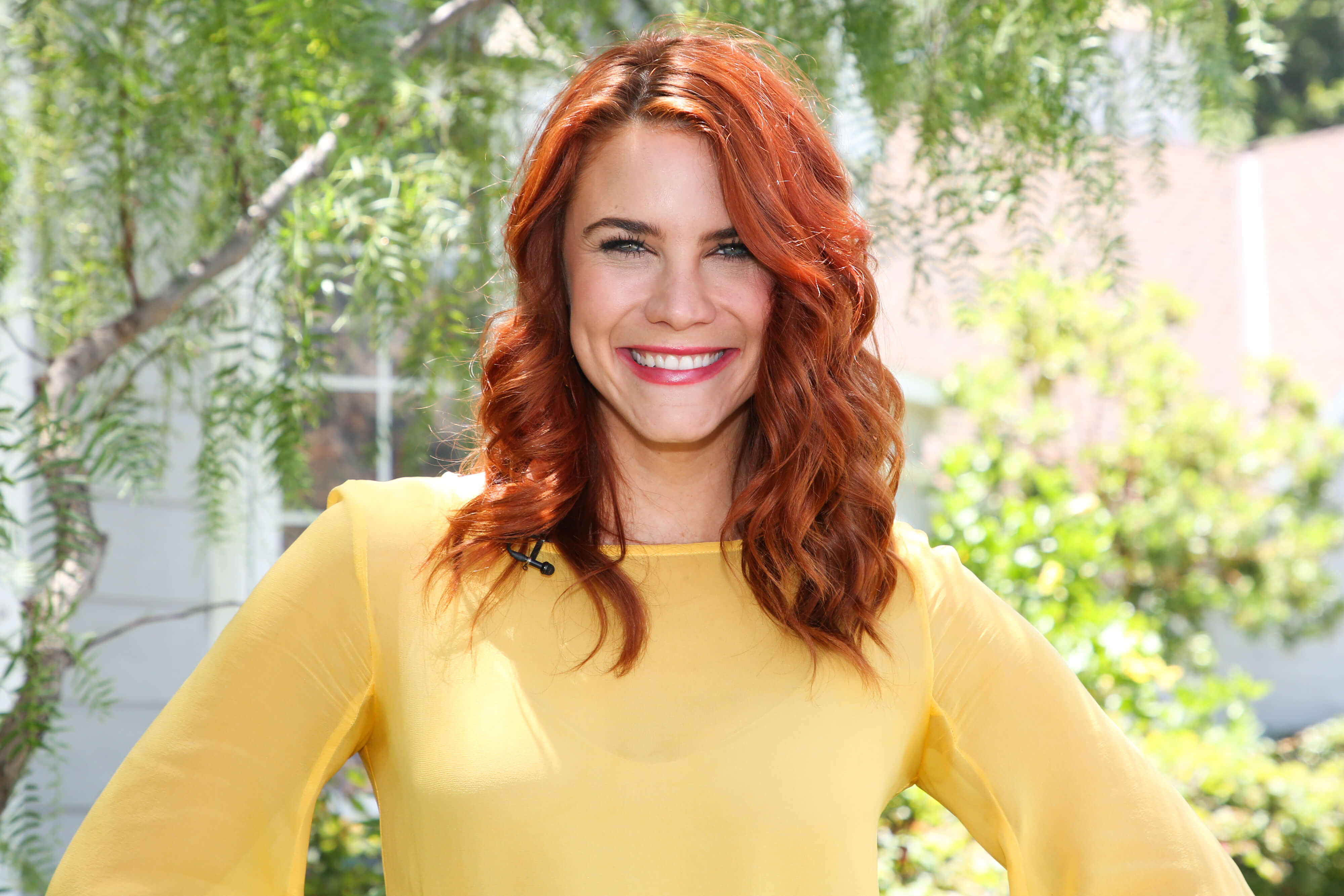 'The Young and the Restless' star Courtney Hope dressed in a yellow blouse; smiling during an outdoor photo.