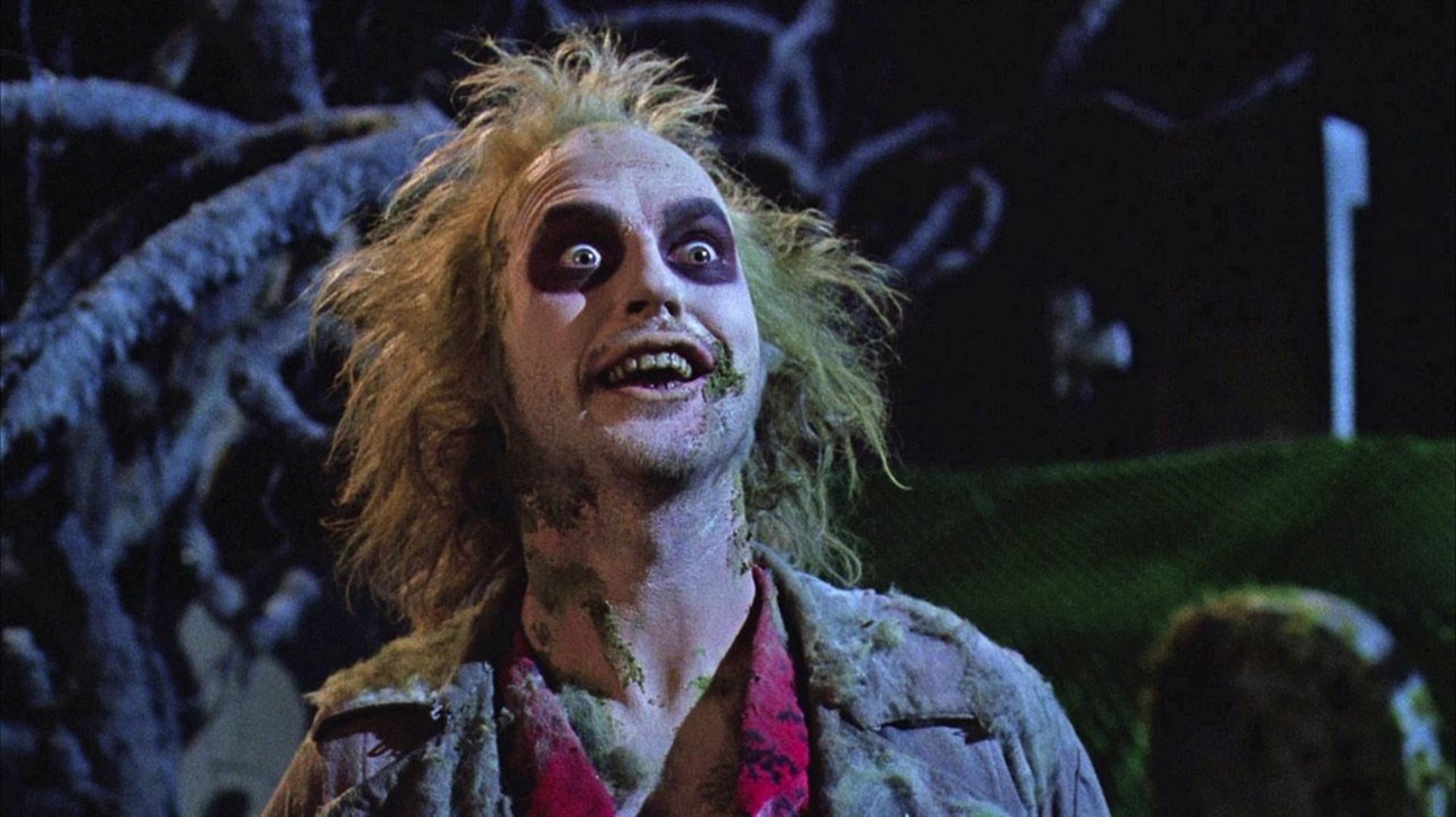 Tim Burton's 'Beetlejuice' Michael Keaton as Beetlejuice with his eyes wide, standing in front of a tree.