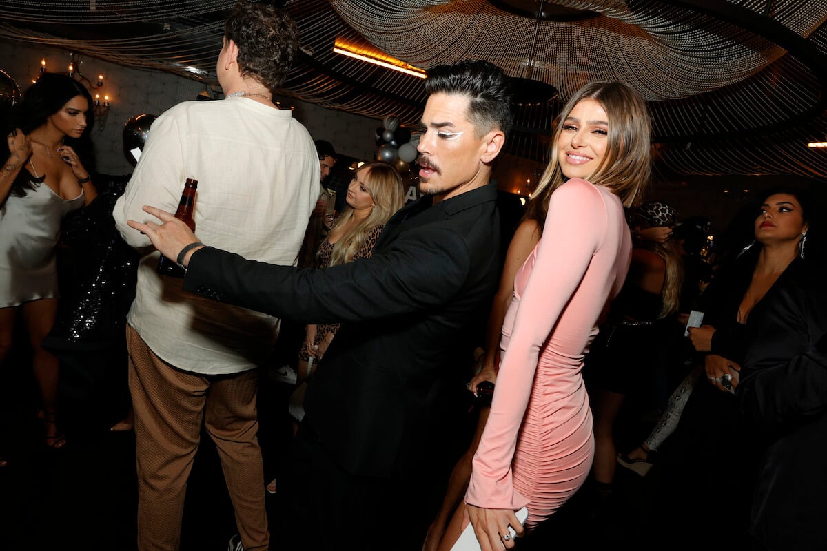 Tom Sandoval with his back up against Raquel Leviss who is smiling