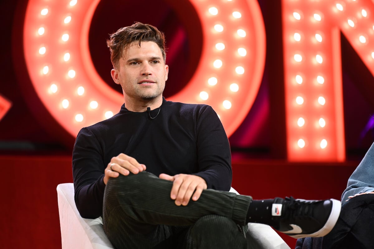 "Vanderpump Rules" star Tom Schwartz sits on stage with his legs crossed at Bravo Con.