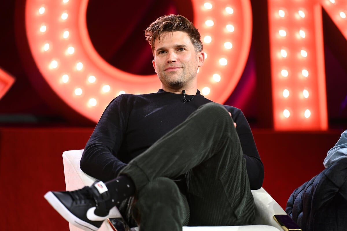 "Vanderpump Rules" star Tom Schwartz sits with his legs crossed on stage.