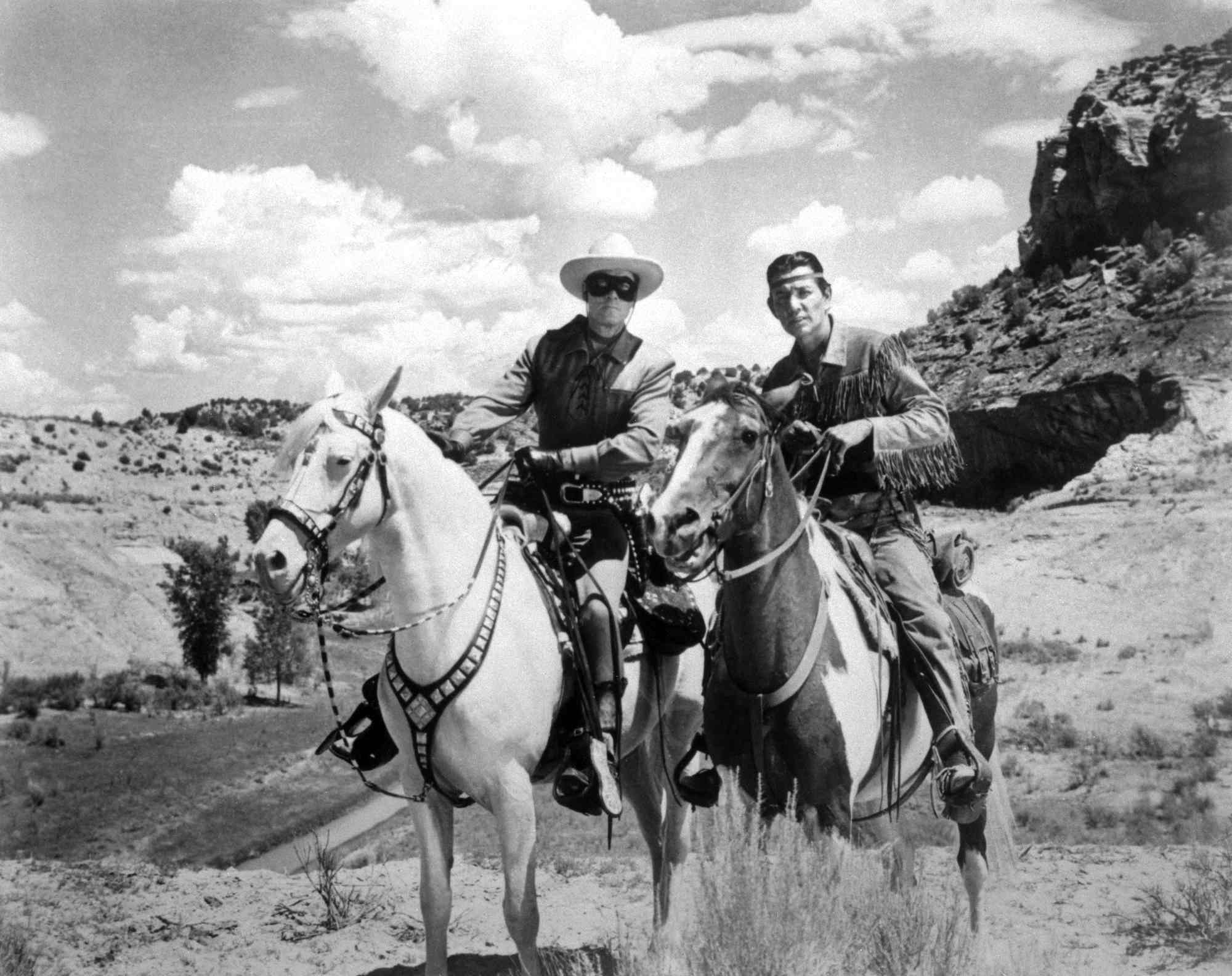 Western television shows 'The Lone Ranger' Clayton Moore as The Lone Ranger and Jay Silverheels as Tonto riding horses in the desert.