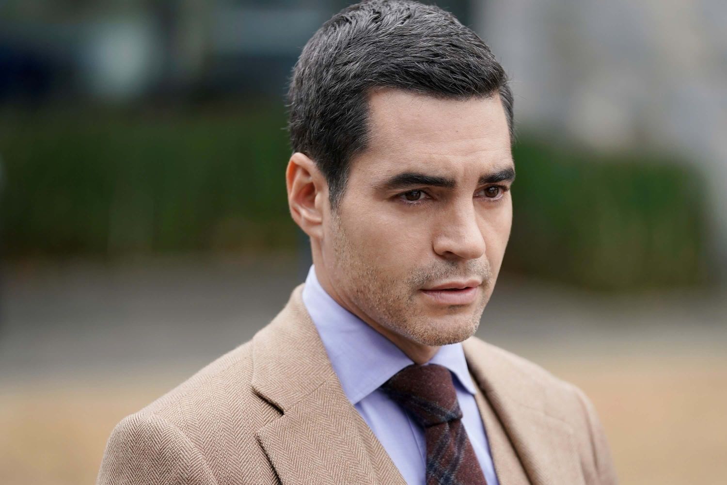 Ramón Rodríguez, in character as Will Trent in 'Will Trent' Season 1, which isn't new tonight, March 7, on ABC. Will wears a tan suit over a light blue button-up shirt and dark red and black plaid tie.