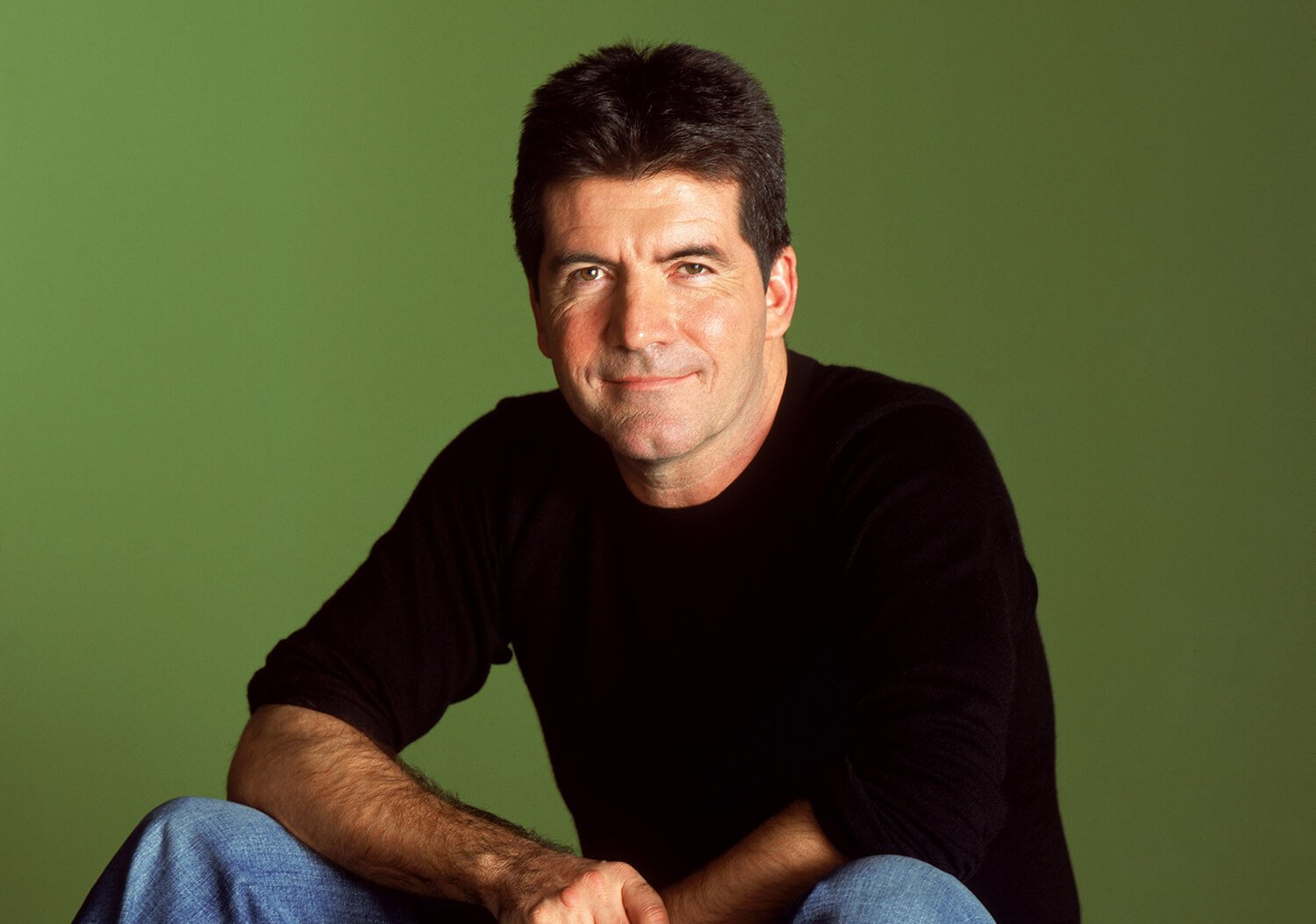 Former American Idol judge Simon Cowell poses against a green backdrop