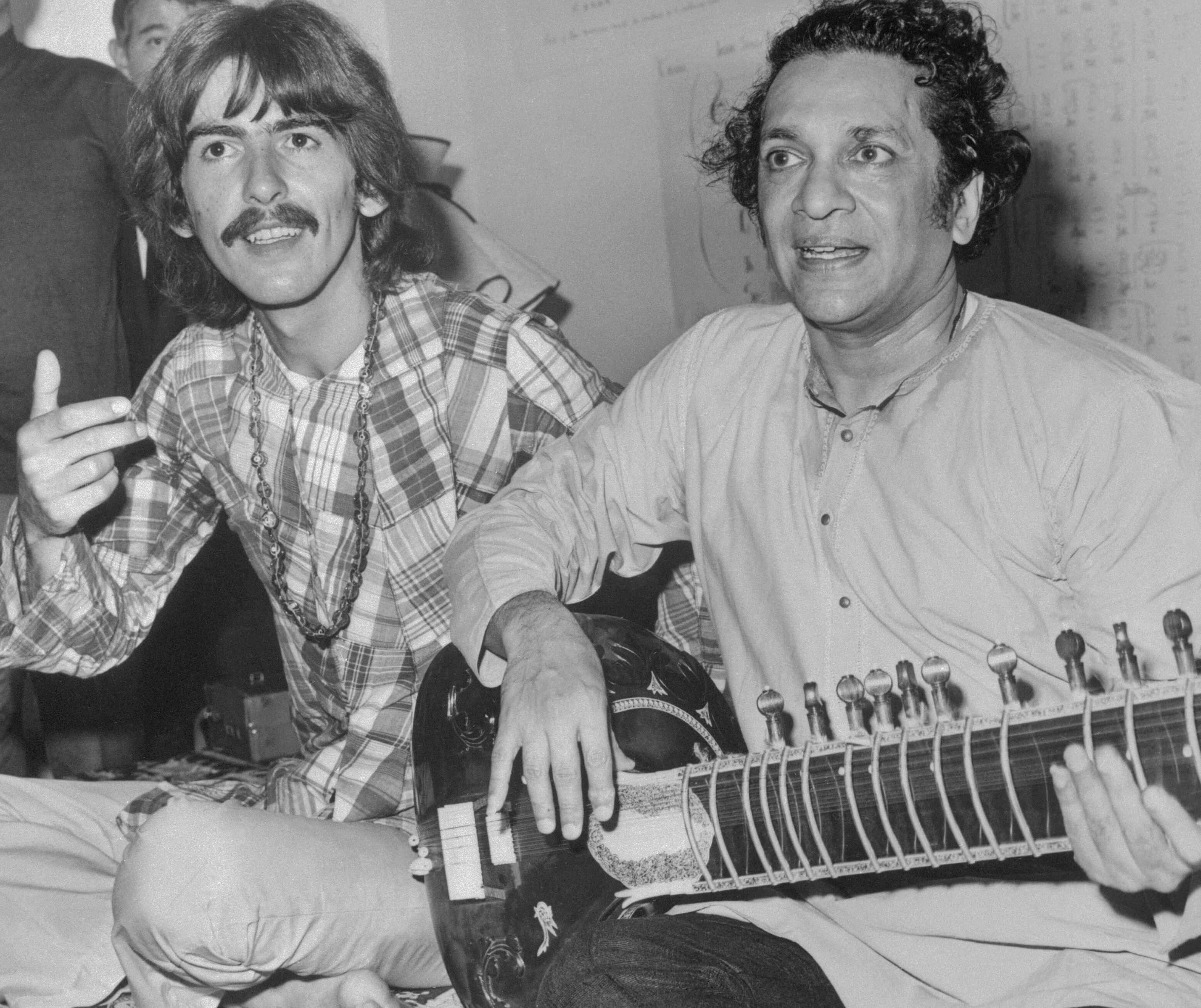 The Beatles' George Harrison next to Ravi Shankar holding a sitar