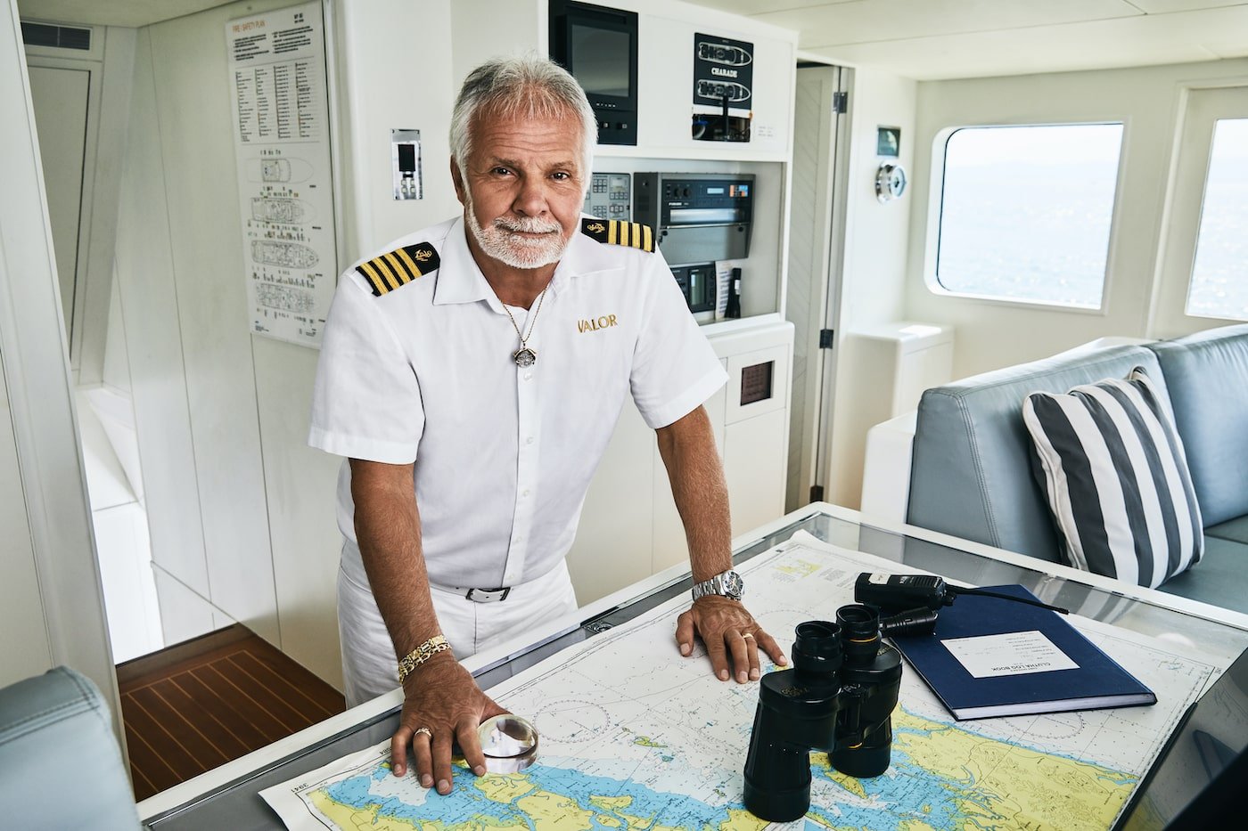 Captain Lee Rosbach from 'Below Deck' stands next to a map