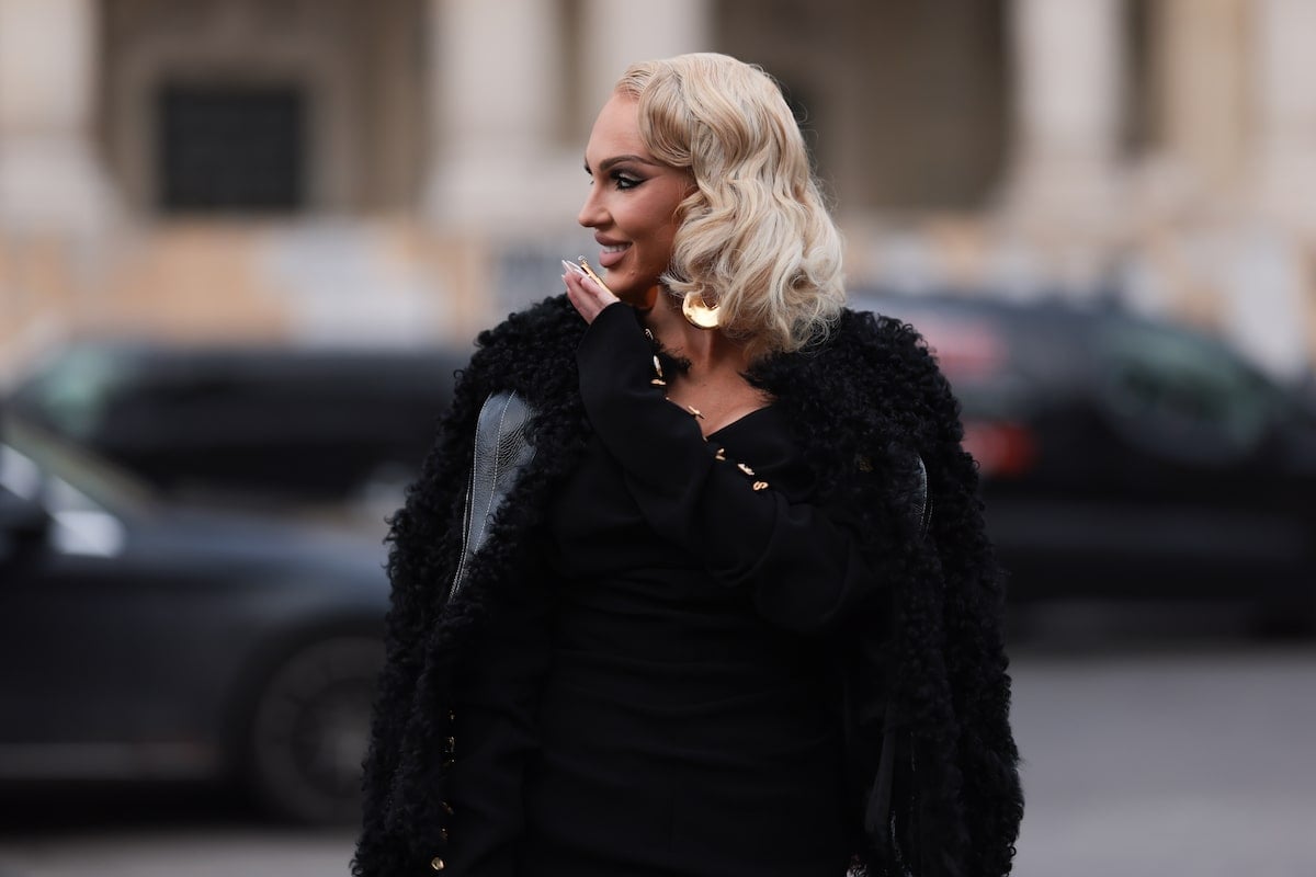 Christine Quinn seen wearing a full black look, a black fur jacket, a black long dress, black leather handbag, Schiaparelli golden earrings, outside Schiaparelli show in Paris, France