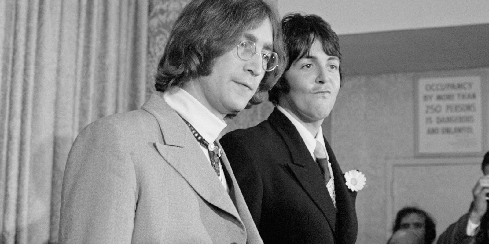 John Lennon and Paul McCartney pose together announcing Apple Corps at a press conference.