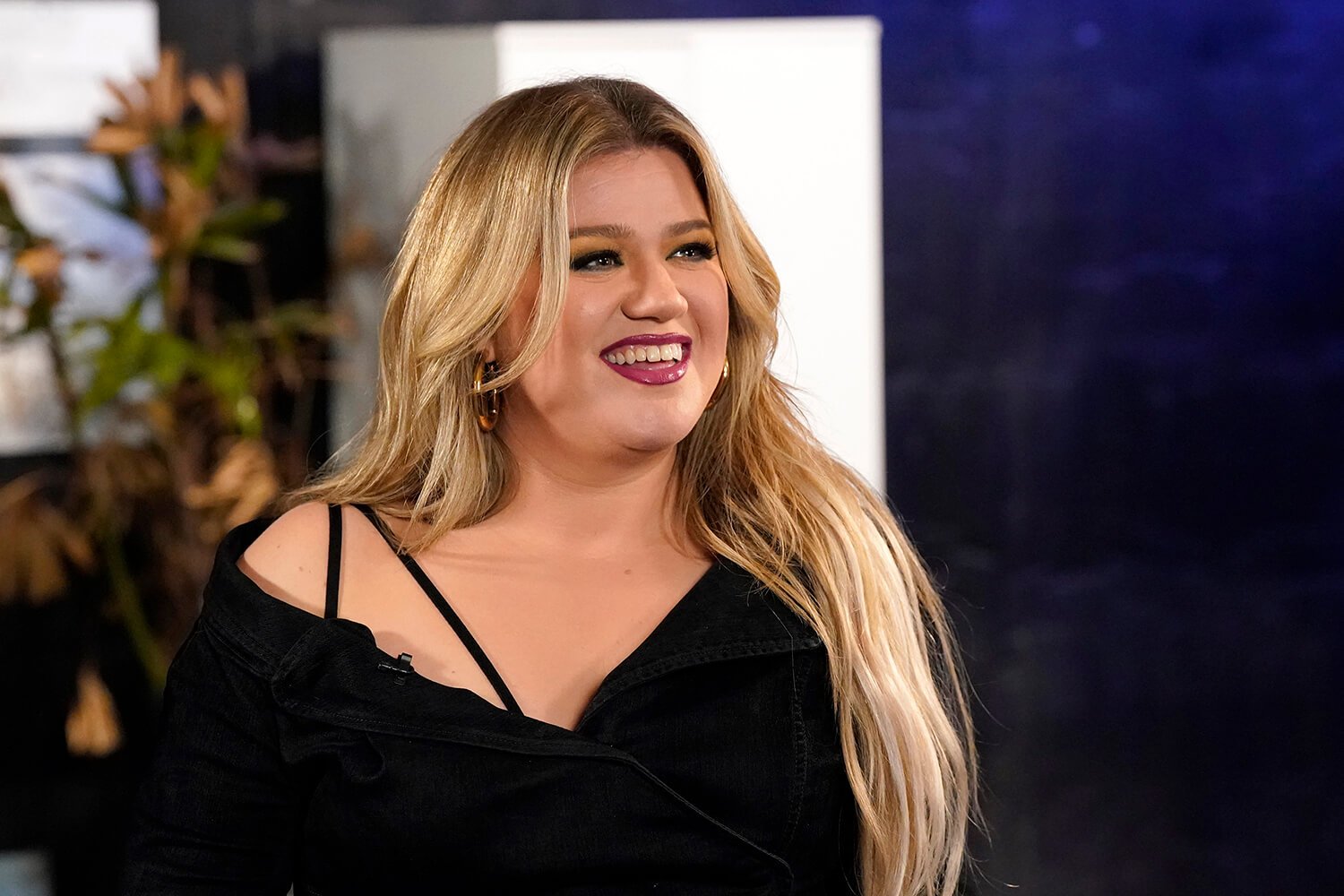 Kelly Clarkson smiles in a black dress on The Voice Season 23