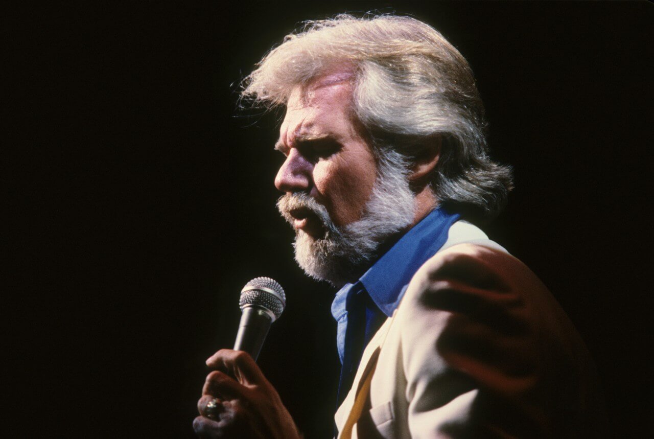 Kenny Rogers holds a microphone during a concert. 