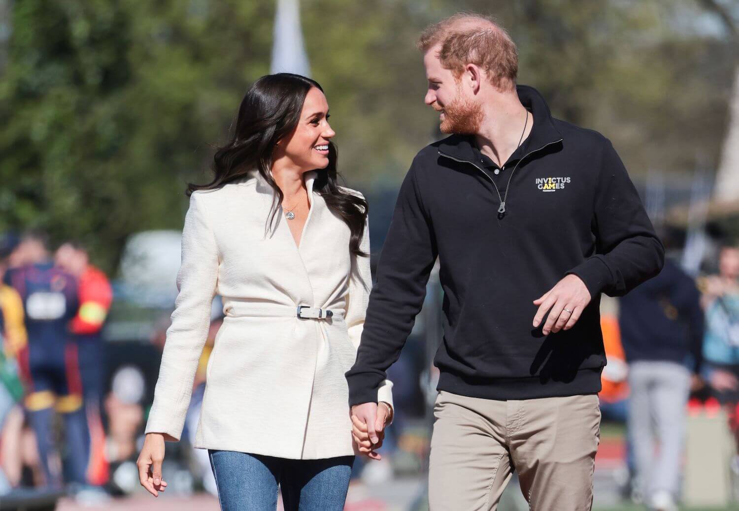 Meghan Markle and Prince Harry look at each other and smile while holding hands