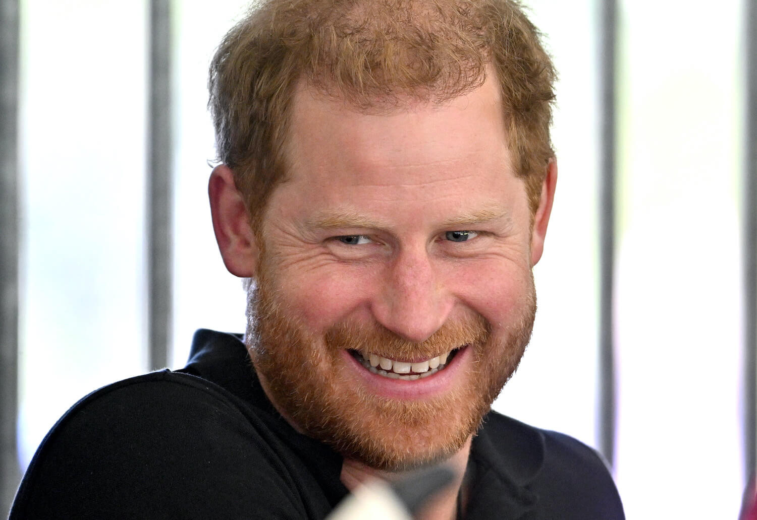 Prince Harry smiles while looking off to the side