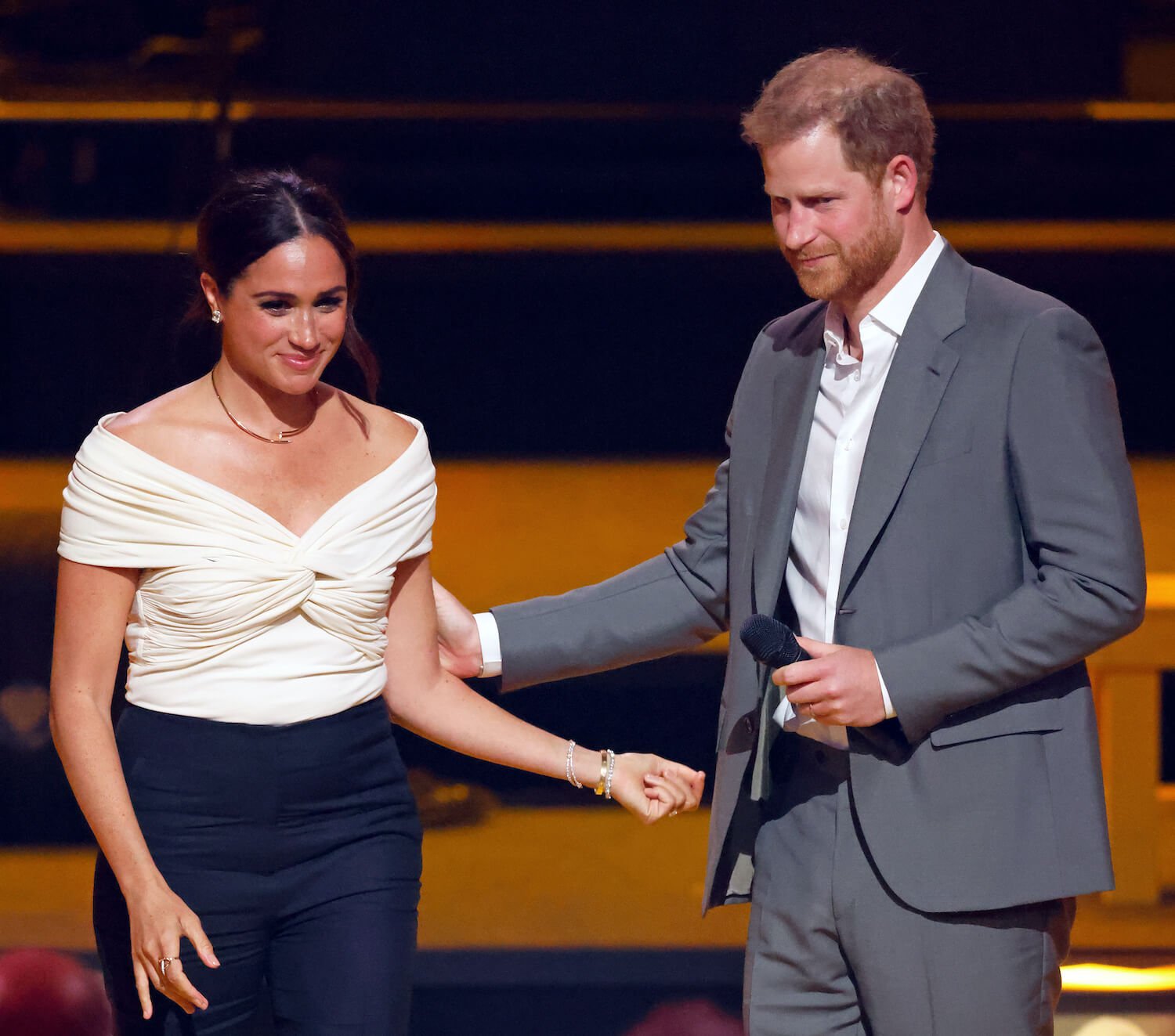 Prince Harry places a hand on Meghan Markle's arm at an event
