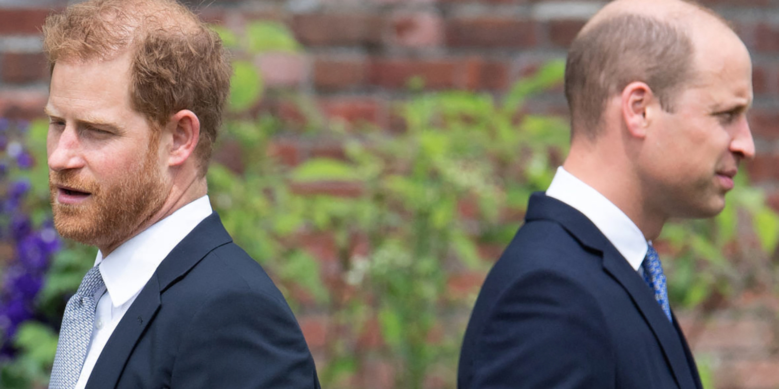 Prince Harry and Prince William stand with their backs toward each other.