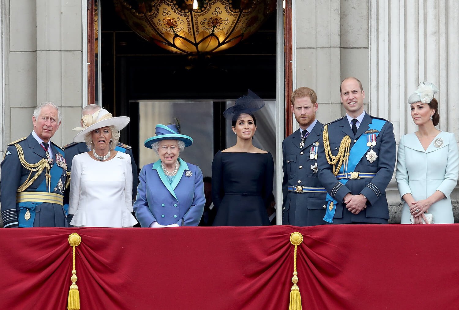 Prince Harry stands with royal family members, King Charles, Camilla Parker Bowles, Queen Elizabeth, Meghan Markle, Prince William, and Kate Middleton on palace balcony
